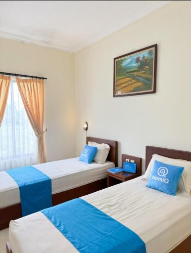 a hotel room with two beds and a window at Adiputra Guesthouse Tata Bumi by HomiQ in Yogyakarta