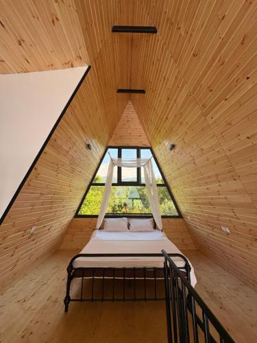 a bed in a wooden room with a window at CottageNEO in Charnali