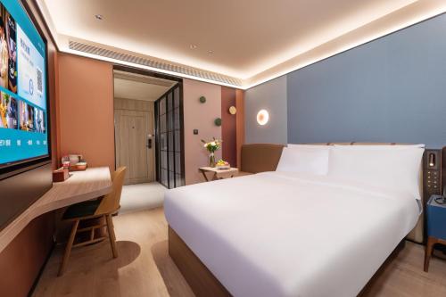 a bedroom with a bed and a desk and a tv at Orange Hotel Hangzhou Joy City in Hangzhou