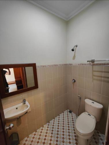 a bathroom with a toilet and a sink and a mirror at Adiputra Guesthouse Tata Bumi by HomiQ in Yogyakarta