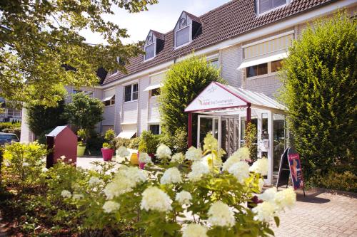 a garden with white flowers in front of a building at NordWest-Hotel Bad Zwischenahn in Bad Zwischenahn