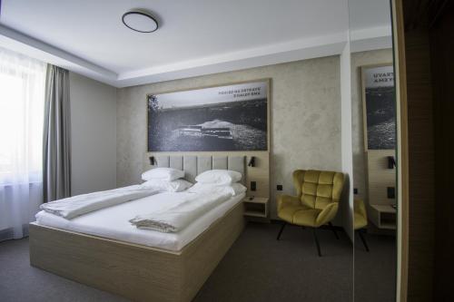 a bedroom with a bed and a yellow chair at Hotel Slezská in Muglinov