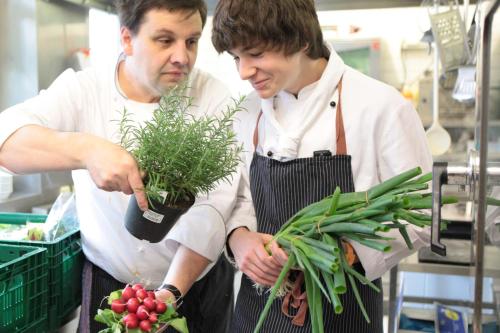 two men standing in a kitchen holding a plant at Hotel-Restaurant Schettel in Olsberg