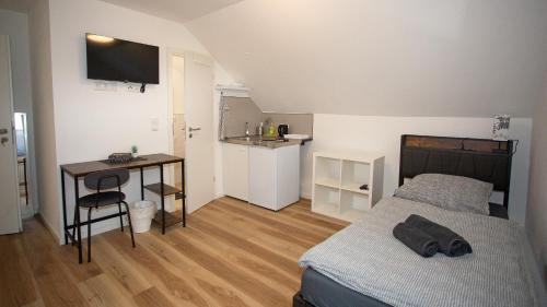 a bedroom with a bed and a desk and a kitchen at Cesar Apartments in Wathlingen