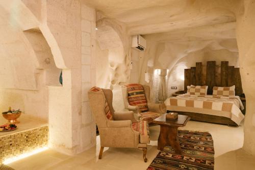 a bedroom with a bed and a chair and a table at Cappadocia Cave Suites in Göreme