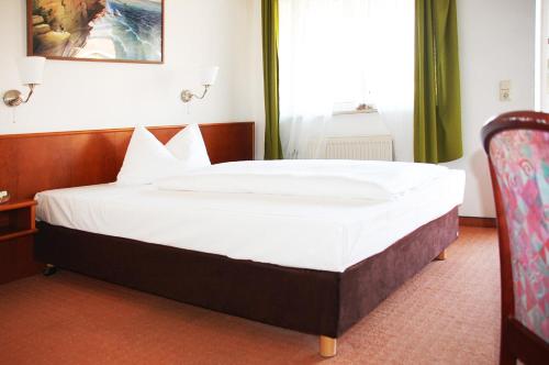 una camera da letto con un grande letto con lenzuola bianche di Hotel Ziegenkrug Rostocker Tor a Rostock