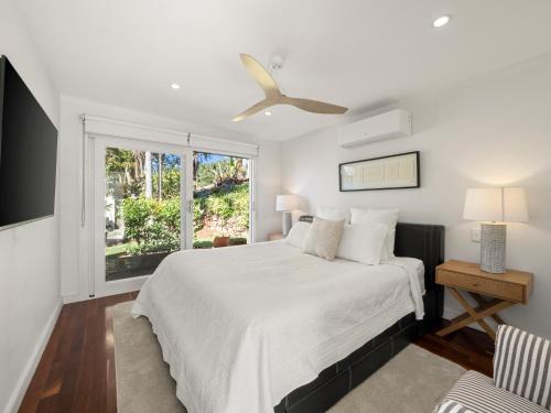 a white bedroom with a bed and a window at Fairview in Rosebank