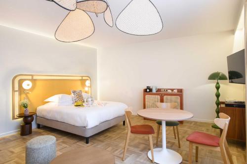 a bedroom with a bed and a table and chairs at Hôtel Rotonde Aix-en-Provence centre in Aix-en-Provence