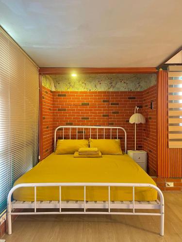 a bedroom with a yellow bed with a brick wall at Old House Homestay in Hanoi