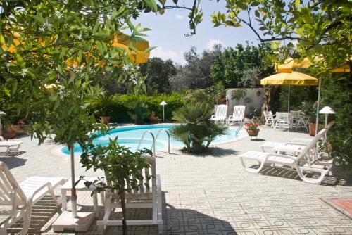 einen Pool mit weißen Stühlen und einem Sonnenschirm in der Unterkunft Hotel Sporting in Vasto