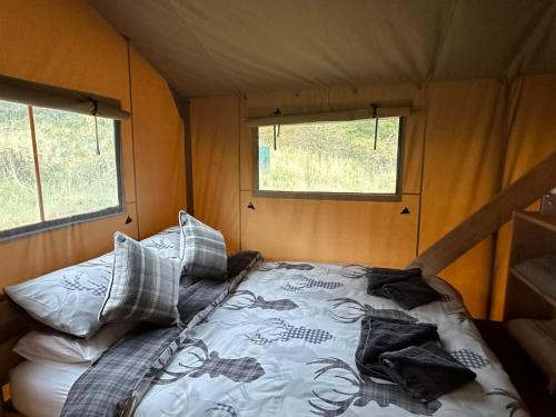 a bed in the middle of a room with two windows at Ecosse Glamping in Crossford