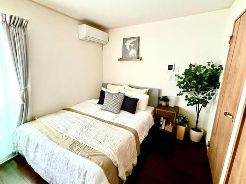 a bedroom with a bed and a plant at Norah Stay Tokyo in Yashio