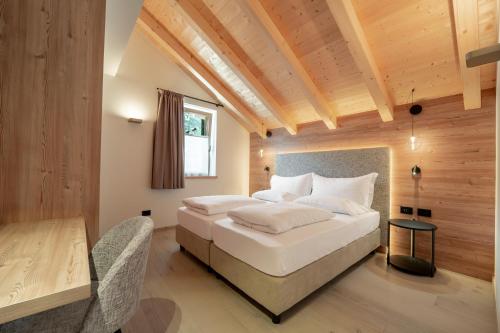 a bedroom with a large white bed and a table at Casa Pencio in Pozza di Fassa