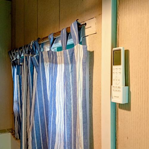 a room with a curtain and a phone on the wall at Salt Bay Kite and Dive Resort in Kalpitiya