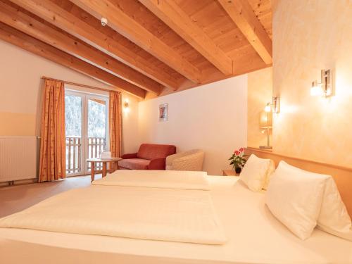 a bedroom with two beds and a chair and a window at Macher's Landhotel in Sankt Jakob in Defereggen