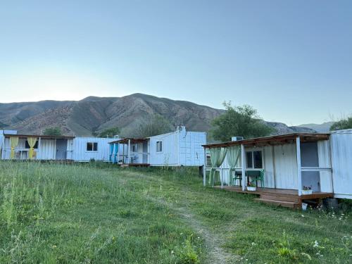 a row of houses in a field with mountains in the background at Qurmety camp in Kurmenty