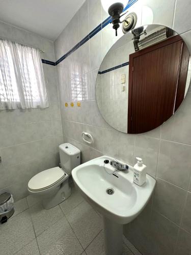 a bathroom with a sink and a toilet and a mirror at Adosado Mar i Pins in Benicarló