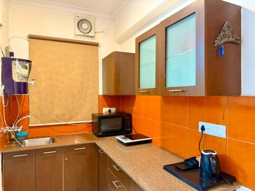 a kitchen with a sink and a microwave at Aloha Serenity By Evara -Ganga View Stays in Rishīkesh