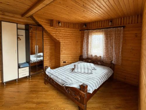 a bedroom with a bed in a wooden room at Mountain House in Mykulychyn