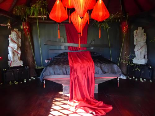 a room with a bed with red umbrellas on it at Le Nid Du Dragon Rouge in Courniou