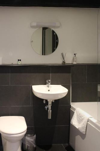 a bathroom with a sink and a toilet and a mirror at The Selsey Arms in West Dean