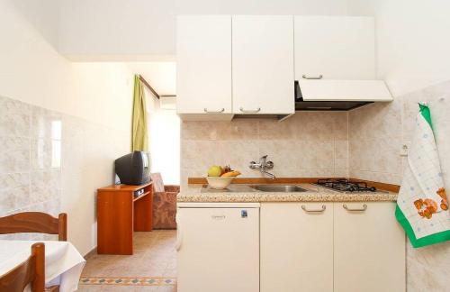 una cocina con armarios blancos y fregadero en Apartments Lili, en Medulin