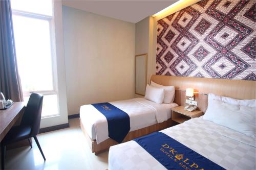 a hotel room with two beds and a desk at D'Kalpa Hotel Demangan Yogyakarta in Yogyakarta