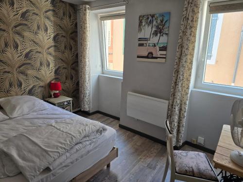 a bedroom with a bed and a table and two windows at duplex centre ville in Privas