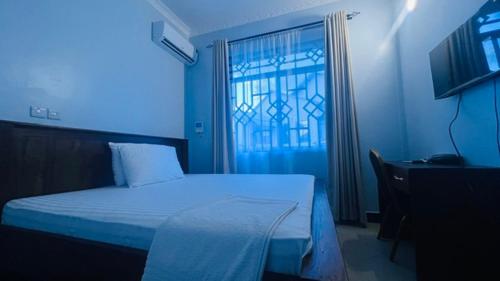 a blue room with a bed and a window at ANITHA EXECUTIVe LODGE in Kibaha