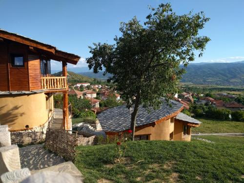 a house with a balcony and a tree on a hill at Eco Village Under the Cliffs in Ilindentsi
