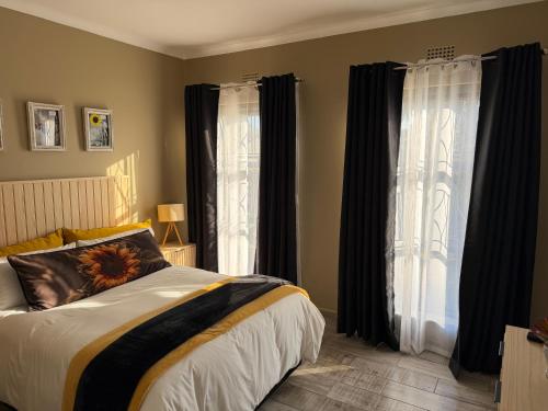a bedroom with a large bed with black curtains at Sweet Willa Bed and Breakfast in Roodepoort
