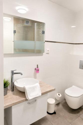 a white bathroom with a sink and a toilet at Family Hotel Albizia Beach in Varna City