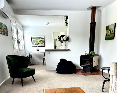 a living room with a green chair and a fireplace at Gone Potty 1 in Alexandra