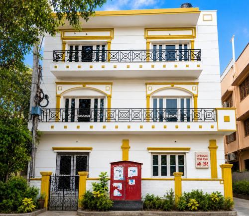 a white house with a red door and yellow trim at Next Generation Guest House in kolkata
