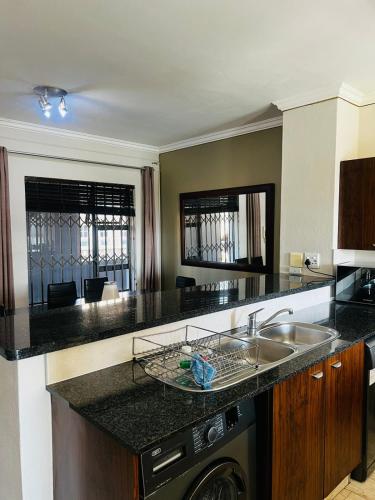 a kitchen with a sink and a dishwasher in it at Prestige Apartments Sandton at Westpoint in Johannesburg