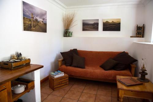 a living room with an orange couch and pictures on the wall at Karoo Khaya in Prince Albert