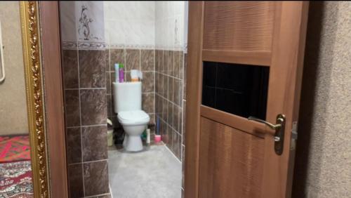 a bathroom with a toilet and a door open at Bars guest House in Barskoon