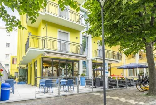 a yellow building with tables and chairs in front of it at Hotel ITALY in Misano Adriatico