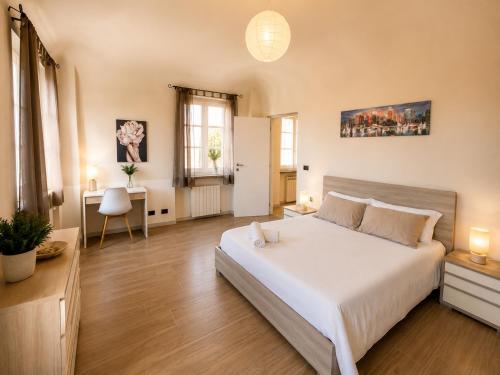 a bedroom with a large white bed and a desk at Novi Outlet Apartment in Novi Ligure