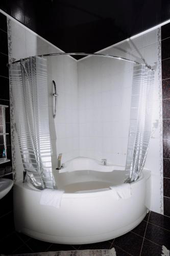 a white bathroom with a tub and a sink at Hotel Gloria in Kostanay