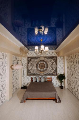 a bedroom with a bed with a blue ceiling at Hotel Gloria in Kostanay