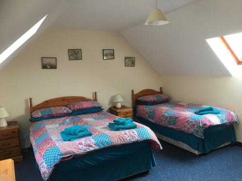 a bedroom with two beds and two lamps and a attic at Buzzards Nest Cottage in Roybridge