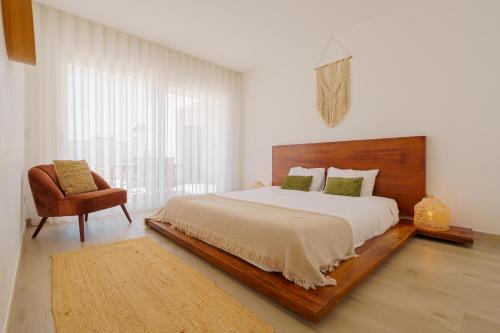 a bedroom with a large bed and a chair at Beach Villa with ocean view in Lourinhã
