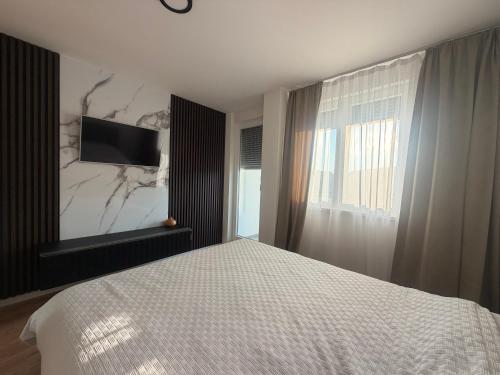 a bedroom with a bed and a television on a wall at Apartman S52 City Centre in Doboj