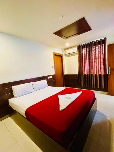 a bedroom with a large bed with a red blanket at Meridian Residency in Ernakulam