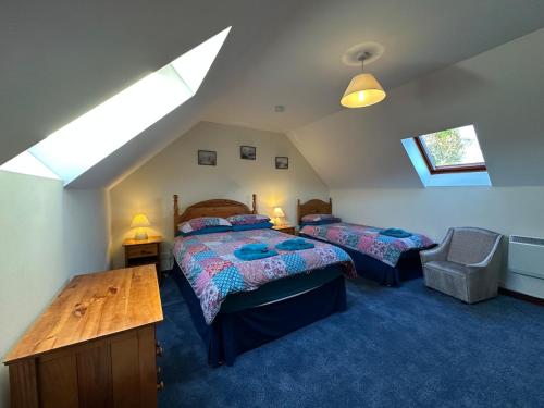 a attic bedroom with two beds and a table at Corrie View in Roybridge