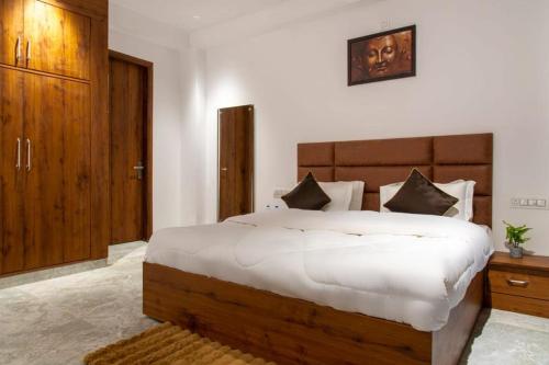 a bedroom with a large white bed with a wooden headboard at The Royals Luxury Apartments Rooftop Restaurant Lift Live Music Sat in Kasauli