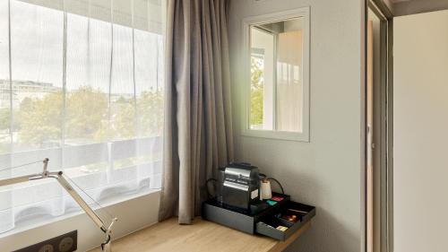 a room with a window and a television on a table at Campanile NATURE - Marne La Vallée - Chelles in Chelles