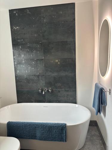 a bathroom with a white tub and a black wall at Swallows Lodge in Bathgate