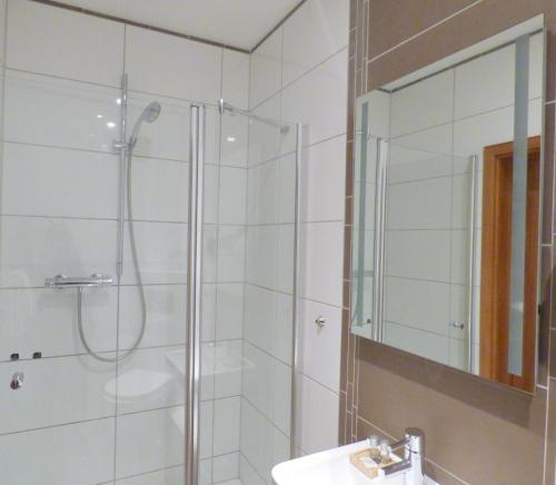 a bathroom with a shower and a sink and a mirror at Hotel Akazienhof in Duisburg